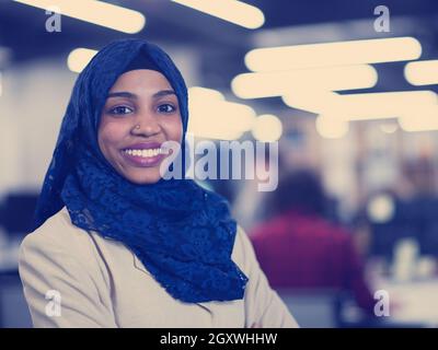 Portrait of young muslim african american female software developer with blue scarf standing at modern startup office Stock Photo