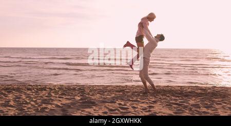 Young couple having fun on beach during autumn sunny day Stock Photo