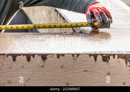 Cement Construction Worker Using Measuring Tape While Forming Pool Coping. Stock Photo