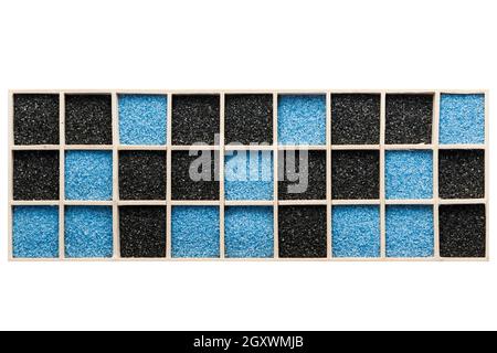 Blue and black decorative sand distributed in a rectangular wooden box with square compartments. Stock Photo