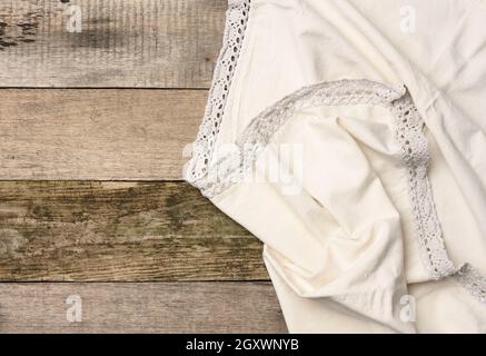 folded beige linen towel on a table made of old gray wooden boards, top view, copy space Stock Photo