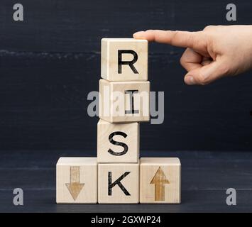 wooden cubes with the inscription risk on a blue background. Risk reduction concept, reinsurance. How to avoid losses, unknown new beginnings in busin Stock Photo
