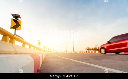 Motion blur of red car driving on curve concrete road with traffic sign. Road trip on summer vacation. Car drive on the street. Summer travel by car. Stock Photo