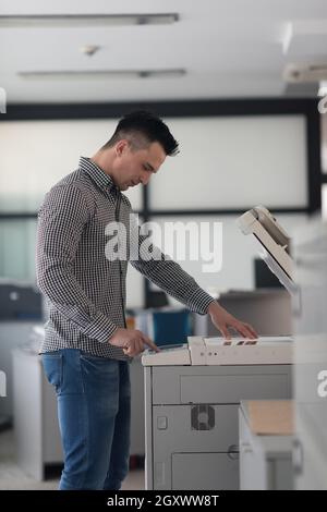 young business man copy documents on copy machine at modern startup office interior, casual clothes Stock Photo