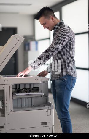 young business man copy documents on copy machine at modern startup office interior, casual clothes Stock Photo