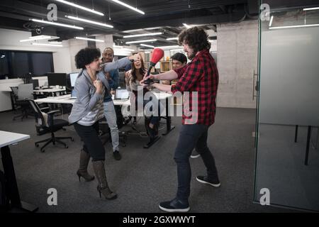 multiethnics startup business team of software developers having fun while boxing at office,excited diverse employees laughing enjoying funny activity Stock Photo