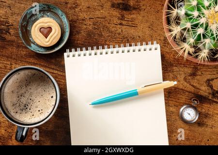 Stationery mockup. Blank notebook with a blue pen and a coffee mug, overhead flat lay shot on a wooden background Stock Photo