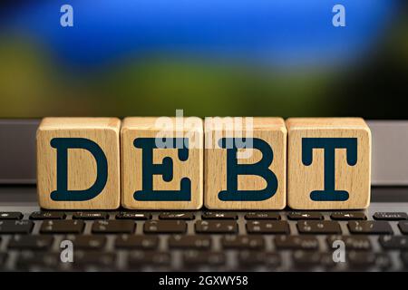 debt theme. wooden cubes with the word debt, on the background of laptop Stock Photo
