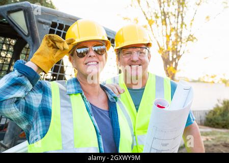 Male and Female Workers With Technical Blueprints at Construction Site Stock Photo