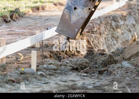 Small Bulldozer Using A Breaker Attachment To Dig Hole Stock Photo