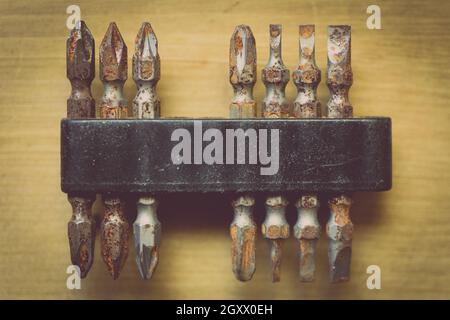 Close up shot of some used rusty screwdriver heads and bits on a wooden background. Stock Photo