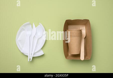 non-degradable plastic waste from disposable tableware and a set of dishes from environmental recycled materials on a green background. The concept of Stock Photo