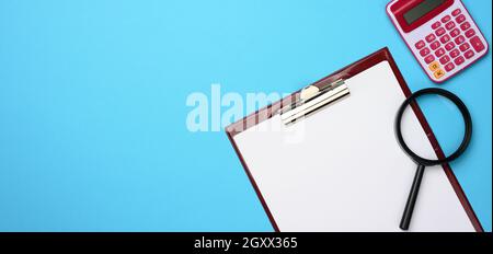 pink calculator, folder with blank white sheets and black magnifier on a blue background. Banner for business, top view Stock Photo