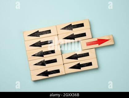 wooden cubes with black arrows in one direction and one block with a red arrow in the opposite direction. Concept of difference, uniqueness of thinkin Stock Photo