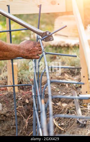 Worker Using Tools To Bend Steel Rebar At Construction Site. Stock Photo