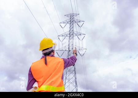 Woman engineers construction worker checking layout on digital ipad or computer. Foreman working  at construction Site with Electric Tower background. Stock Photo