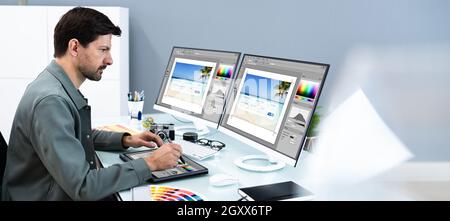 Designer And Photographer Using Multiple Computer Screens Stock Photo