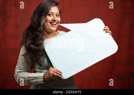Beautiful happy smiling young Indian girl with empty sign board - concept of announcement of promotional offfers and deals during dewali festival Stock Photo