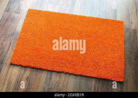 Blank Orange Welcome Mat On Wood Floor Background Ready For Your Own Text. Stock Photo