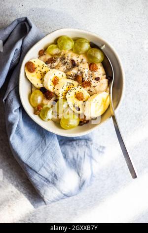 Overhead view of a Bowl of porridge with fresh banana, grapes, goji berries, chia seeds and raisins Stock Photo