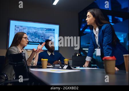 Coworkers on business negotiations in night office. Sleepy male and female managers, dark business center interior on background, modern workplace Stock Photo