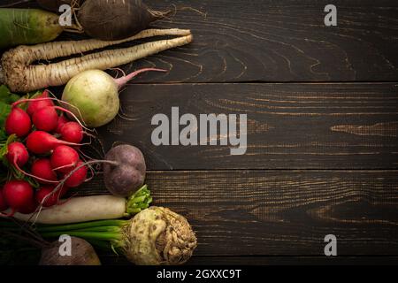 Root vegetables on a wooden background, different types of radish with beetroot and parsley, organic farm vegetables Stock Photo