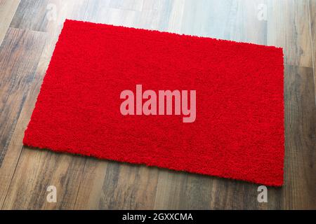 Blank Red Welcome Mat On Wood Floor Background Ready For Your Own Text. Stock Photo