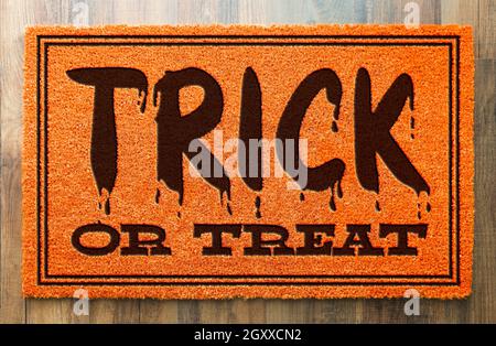 Trick Or Treat Halloween Orange Welcome Mat On Wood Floor Background. Stock Photo