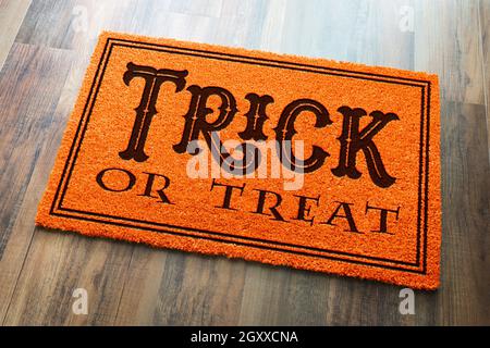 Trick Or Treat Halloween Orange Welcome Mat On Wood Floor Background. Stock Photo