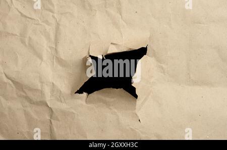 brown crumpled paper with a hole, edges torn and curved. Abstract background Stock Photo