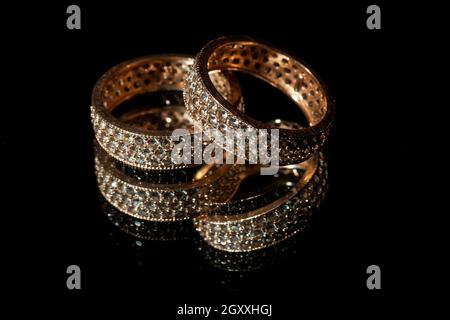 Wedding rings lie on a mirror, black background Stock Photo