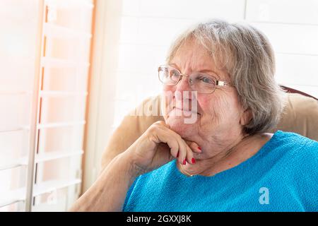 Content Senior Woman Gazing Out of Her Window. Stock Photo