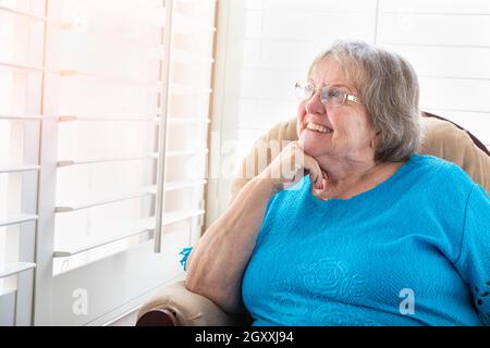 Content Senior Woman Gazing Out of Her Window. Stock Photo