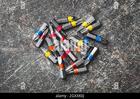 Set of screwdriver bits. Various types of screwdriver  heads isolated on black table. Top view. Stock Photo