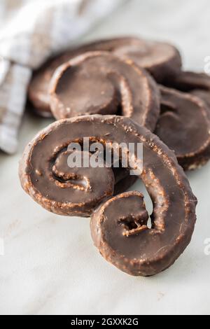 Sweet pastry palmeritas with chocolate icing on white table. Stock Photo