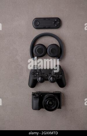 Overhead flat lay of black technology devices and gadgets on a grey background
