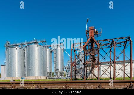 Round metal grain elevator bins next to railroad tracks Stock Photo