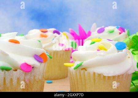 Cupcakes with brightly colored sprinkles on blue background Stock Photo