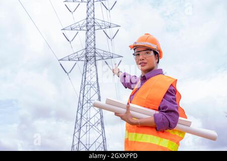 Woman engineers construction worker checking layout on digital ipad or computer. Foreman working  at construction Site with Electric Tower background. Stock Photo