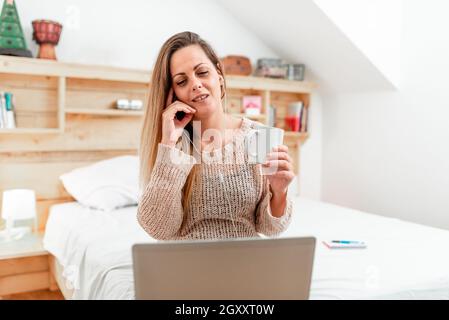 Casual Lady Having Call From Her Room Using A Computer With Headset, Business Woman Having A Vedio Conference Meeting Through A Laptop And Wired Headp Stock Photo