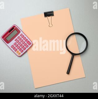 pink calculator, folder with blank  sheets and black magnifier on a gray background. Banner for business, top view Stock Photo