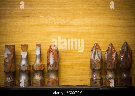 Close up shot of some used rusty screwdriver heads and bits on a wooden background. Stock Photo