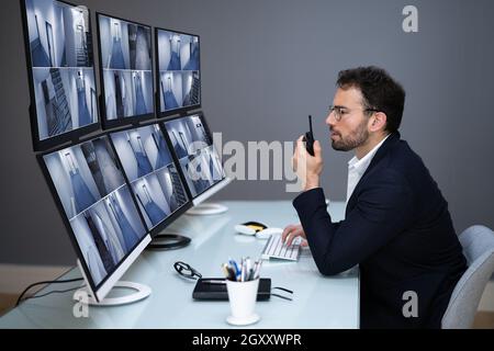 Security System CCTV Monitor Room. Man Using Walkie Talkie Stock Photo