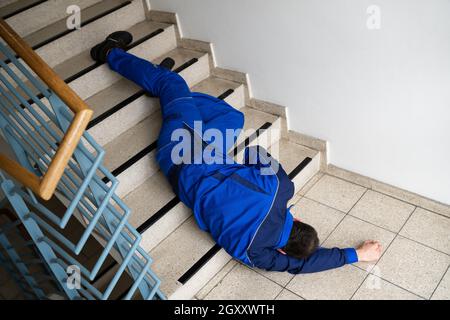 Worker Man Lying On Staircase After Slip And Fall Accident Stock Photo