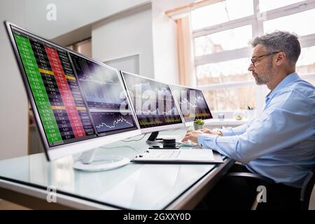 Stock Exchange Analyst Using Multiple Computer Screens Stock Photo