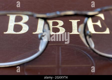 A reading glasses lying on the cover of the Bible, close up. Stock Photo