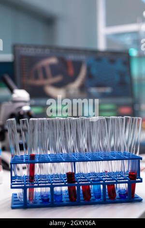 Close up of tube rack with test tubes on laboratory desk. Transparent lab glassware with liquid blood, dna and solution prepared for research analysis in microbiology industry space Stock Photo