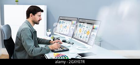 Designer And Photographer Using Multiple Computer Screens Stock Photo