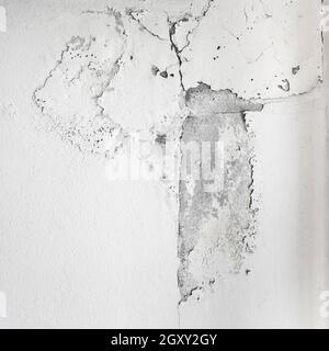 White cracked paint on wall. Peeling painted wall, texture, grunge background, cracked paint with white wall with window. Stock Photo
