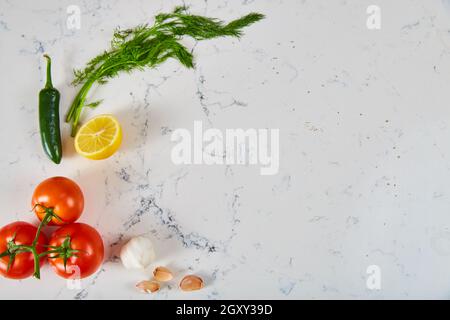 Fresh herbs and produce on white marble surface Stock Photo